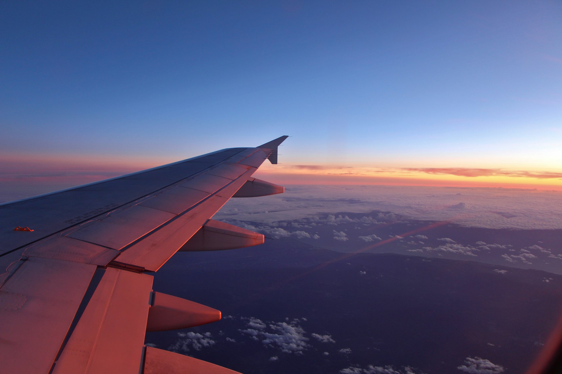 Aripa unui avion de pasageri deasupra norilor, la apus